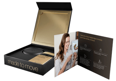 Open orthodontic treatment package box displaying black case, informational brochures, and patient materials.